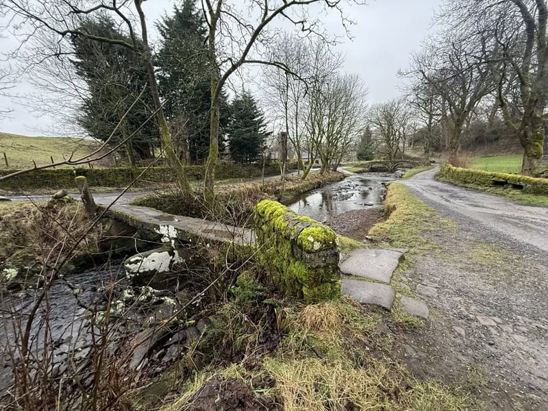 Historic stone bridge over a small stream in Wycoller village, England.